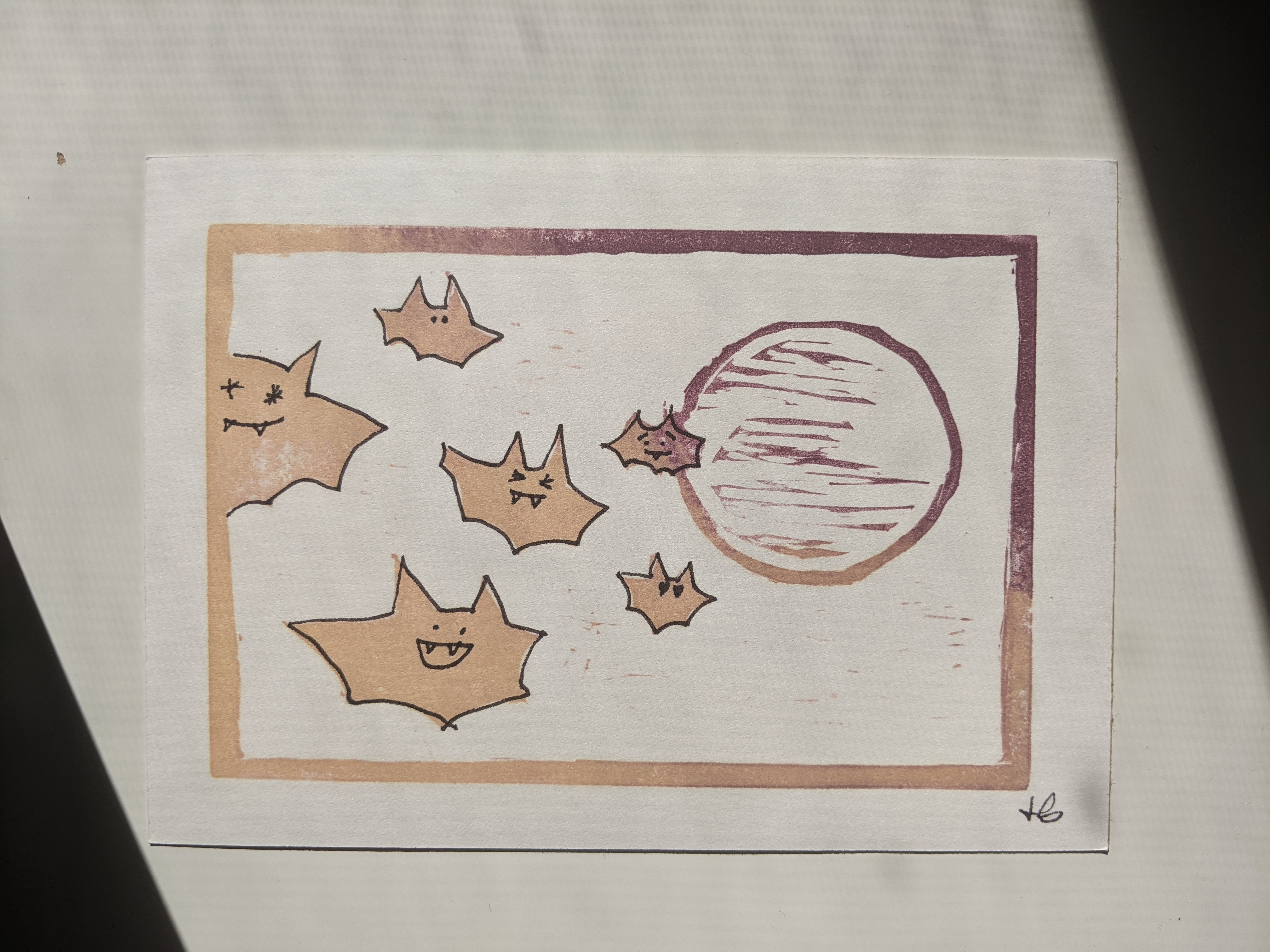 A small group of cute bats flying in front of a moon.