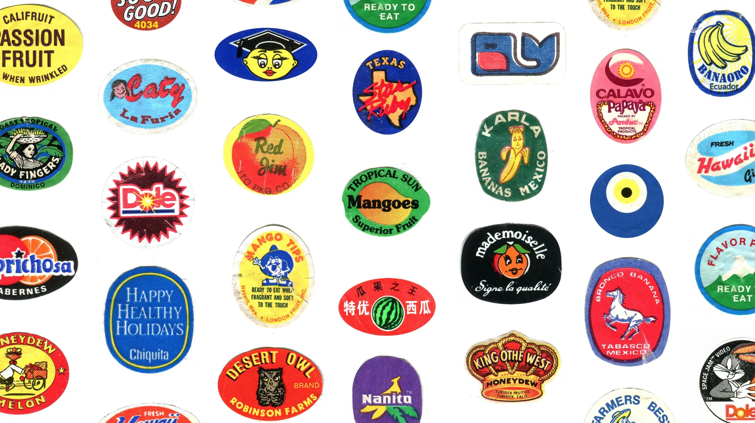 Lots of brightly-coloured fruit stickers scattered on a white background.