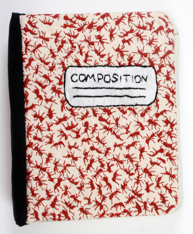 The cover of a notebook made of fabric, covered in embroidered ants.